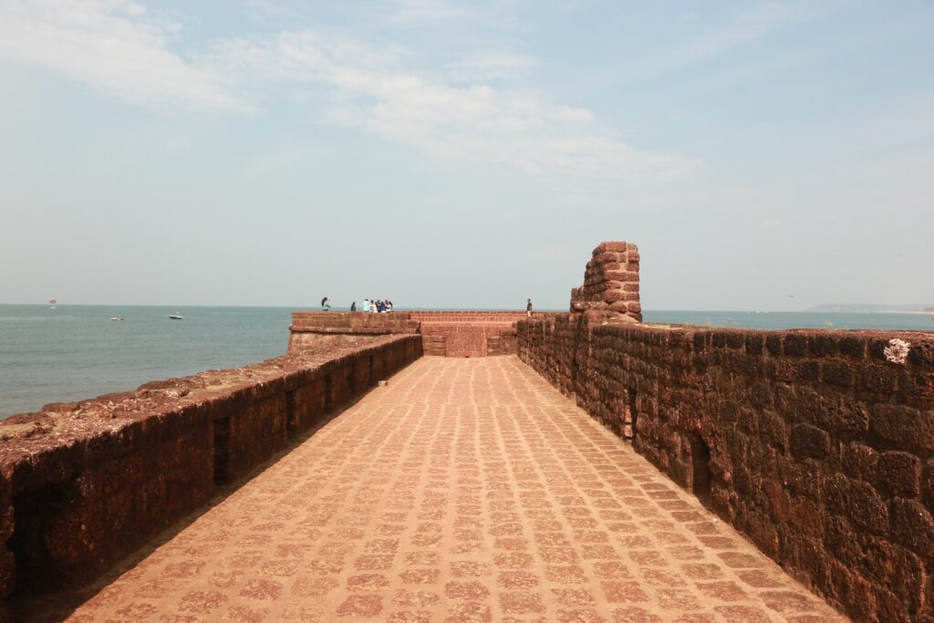 a brick walkway leading to the ocean on a sunny day- Fort Aguada, Candolim