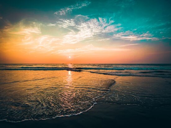 the sun is setting over the ocean on the beach- goa
